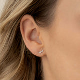 Close-up of an ear wearing Diamond Climber Stud Earrings White Gold - Rhea with curved row of sparkling diamonds