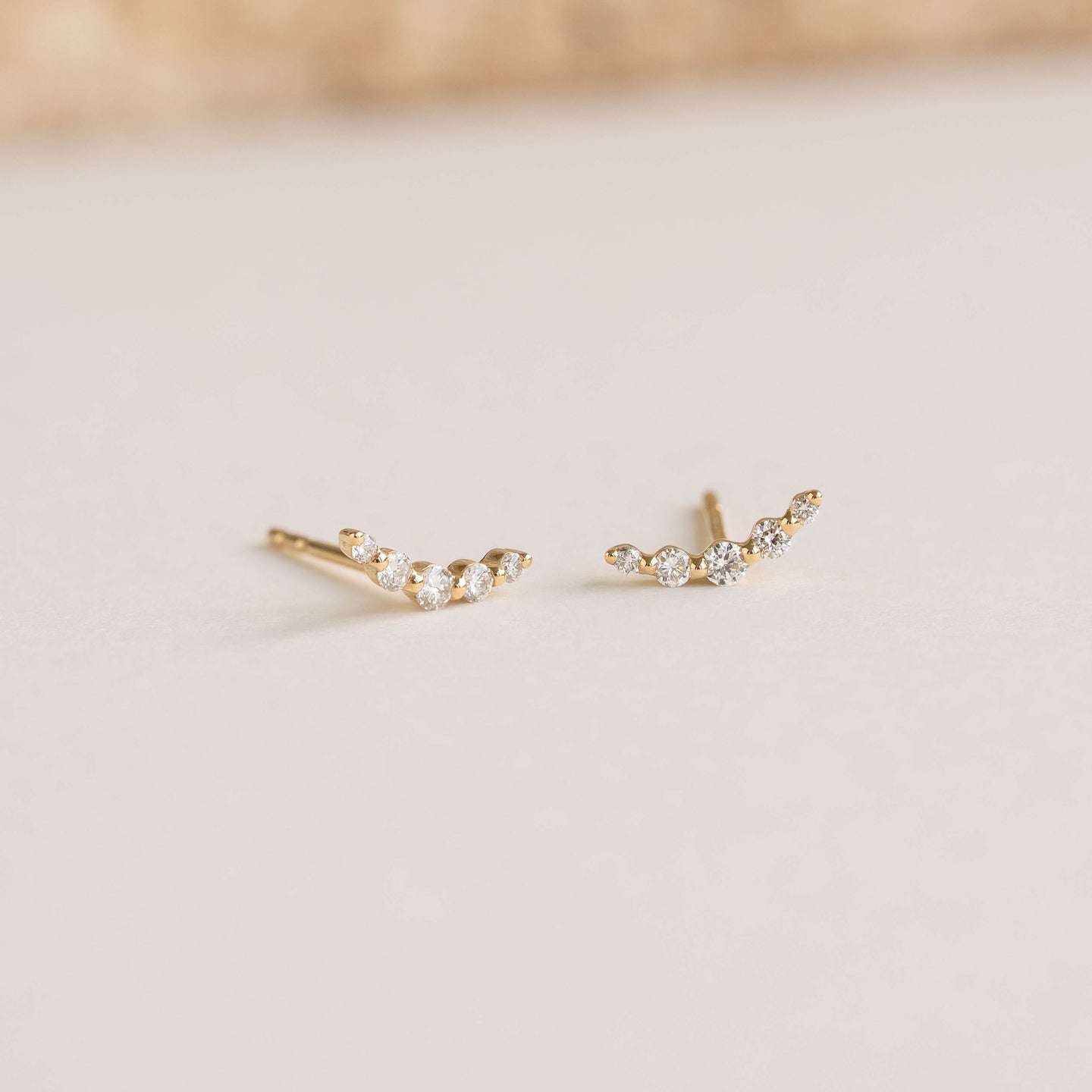 Close-up of Diamond Climber Stud Earrings 14k Gold - Rhea featuring small round diamonds on a soft beige surface