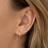Close-up of an ear wearing Diamond Climber Stud Earrings 14k Gold - Rhea with small round diamonds and gold hoop