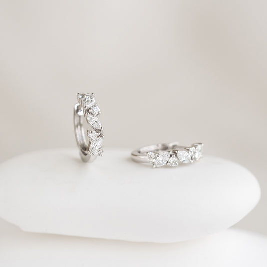 Close-up of Marquise and Round Diamond Huggie Earrings White Gold - Rosa displayed on a smooth white surface with soft background
