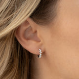 Close-up of an ear wearing a diamond hoop earring with blonde hair.