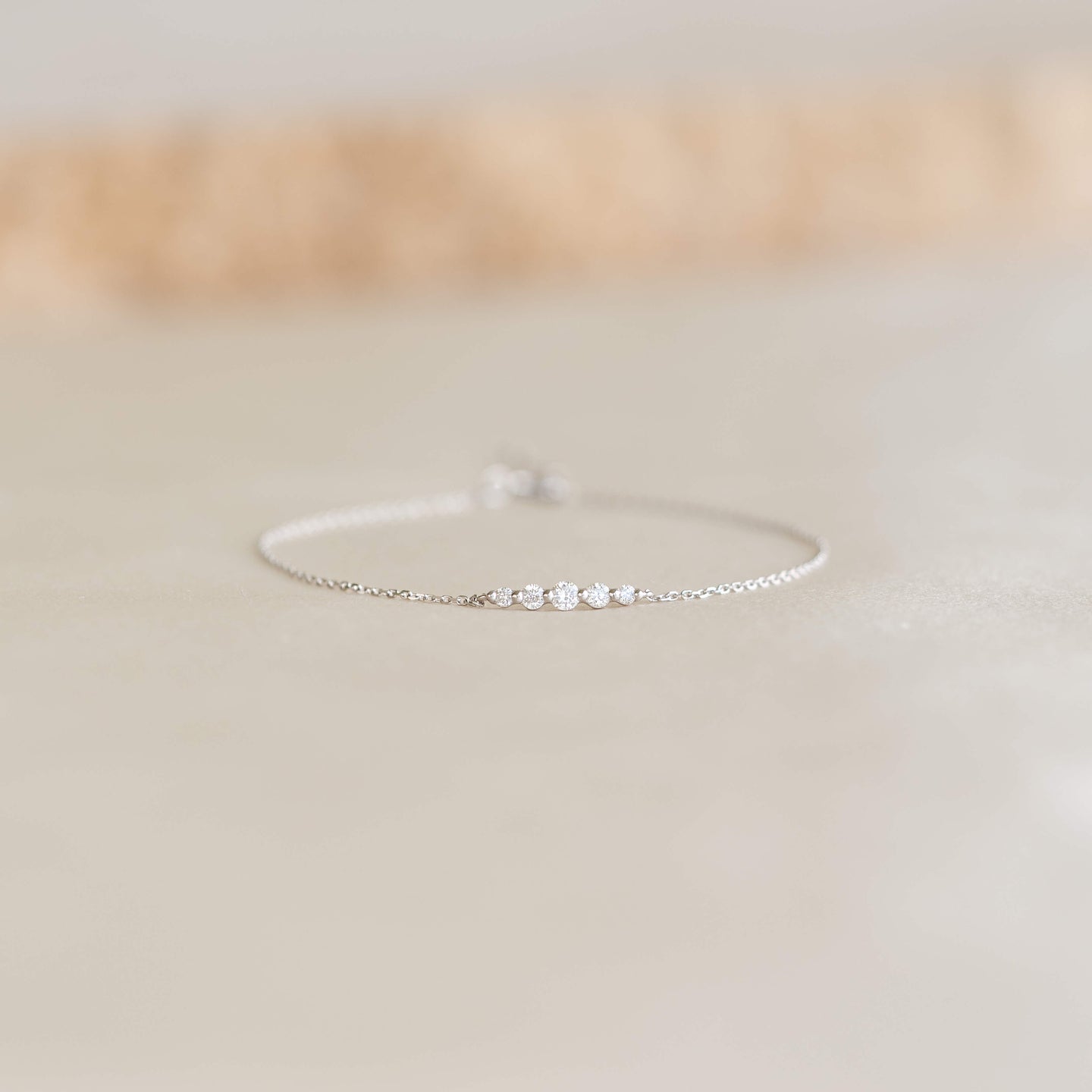 Close-up of a delicate Graduated Diamond Bracelet White Gold - Tamsin featuring five small diamonds on a fine chain