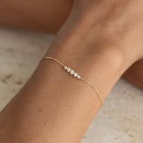 Close-up of wrist wearing the Graduated Diamond Bracelet 14k Gold - Tamsin with a delicate gold chain and sparkling diamonds