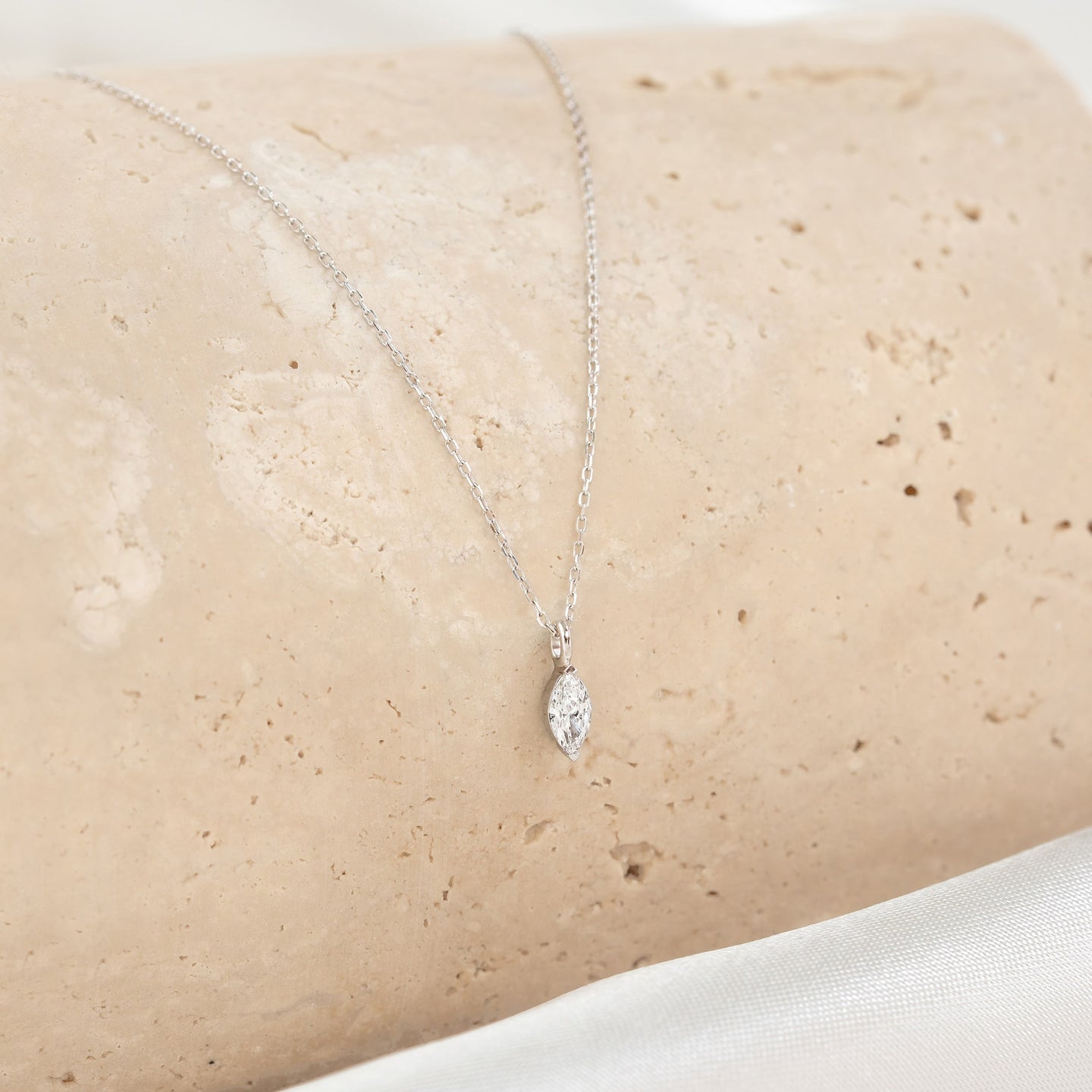 Close-up of a marquise diamond pendant on a delicate chain from the Marquise Diamond Necklace White Gold - Violetta displayed on stone
