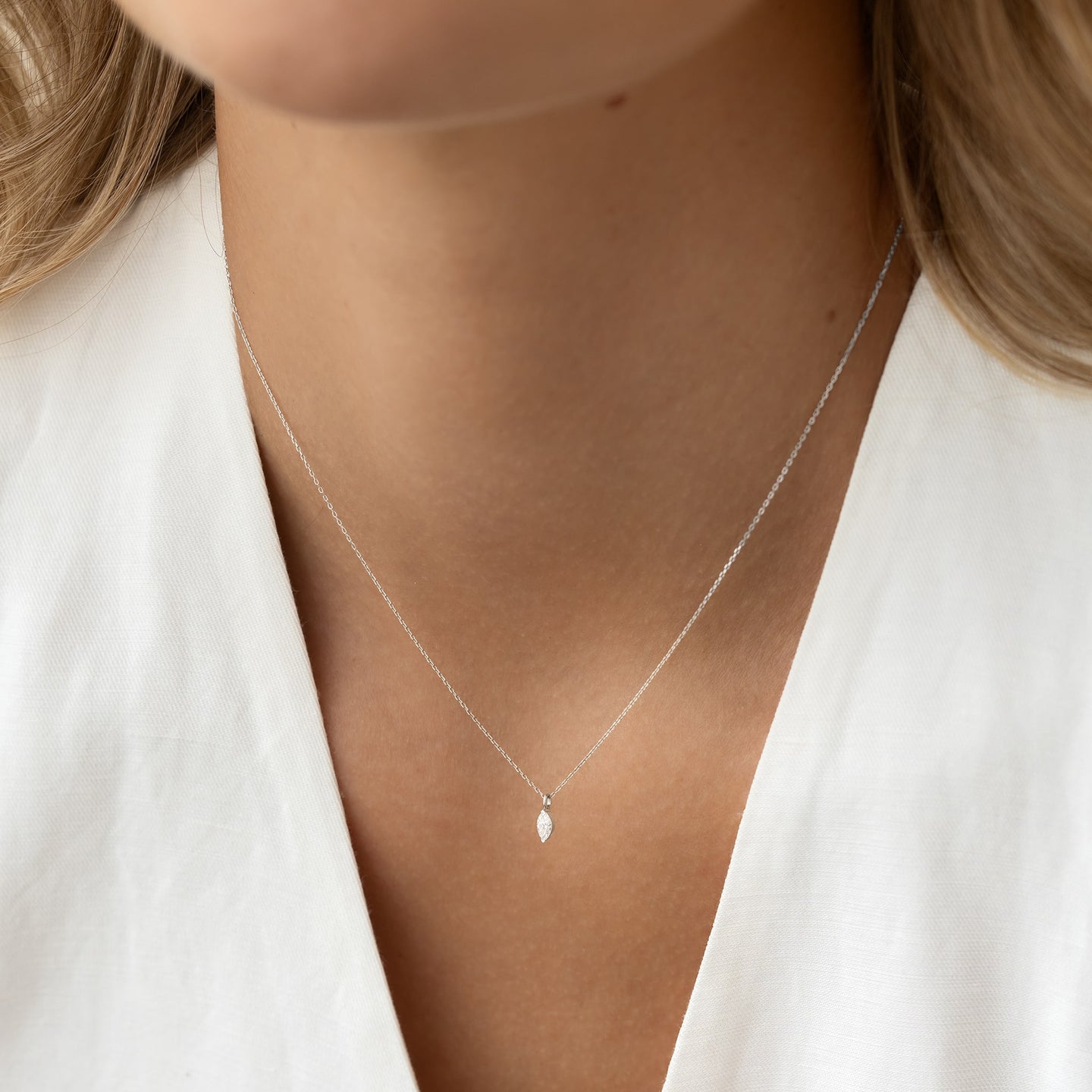 Close-up of a woman wearing a Marquise Diamond Necklace White Gold - Violetta with a delicate pendant on a fine chain