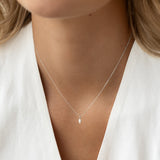 Close-up of a woman wearing a Marquise Diamond Necklace White Gold - Violetta with a delicate pendant on a fine chain