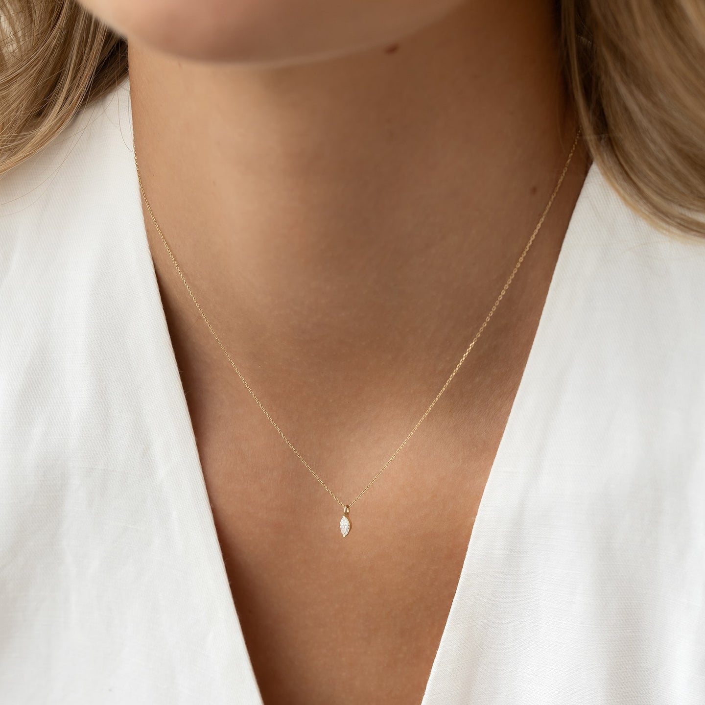 Close-up of a woman wearing the Marquise Diamond Necklace 14k Gold - Violetta with a delicate marquise diamond pendant