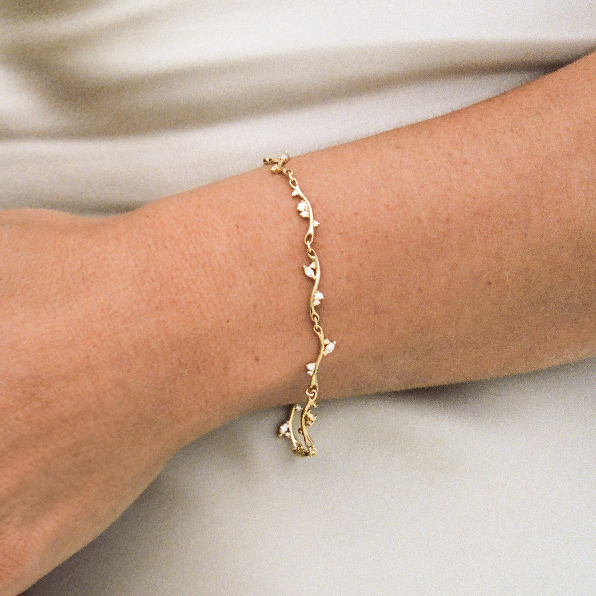 Gold bracelet on a wrist with a neutral background