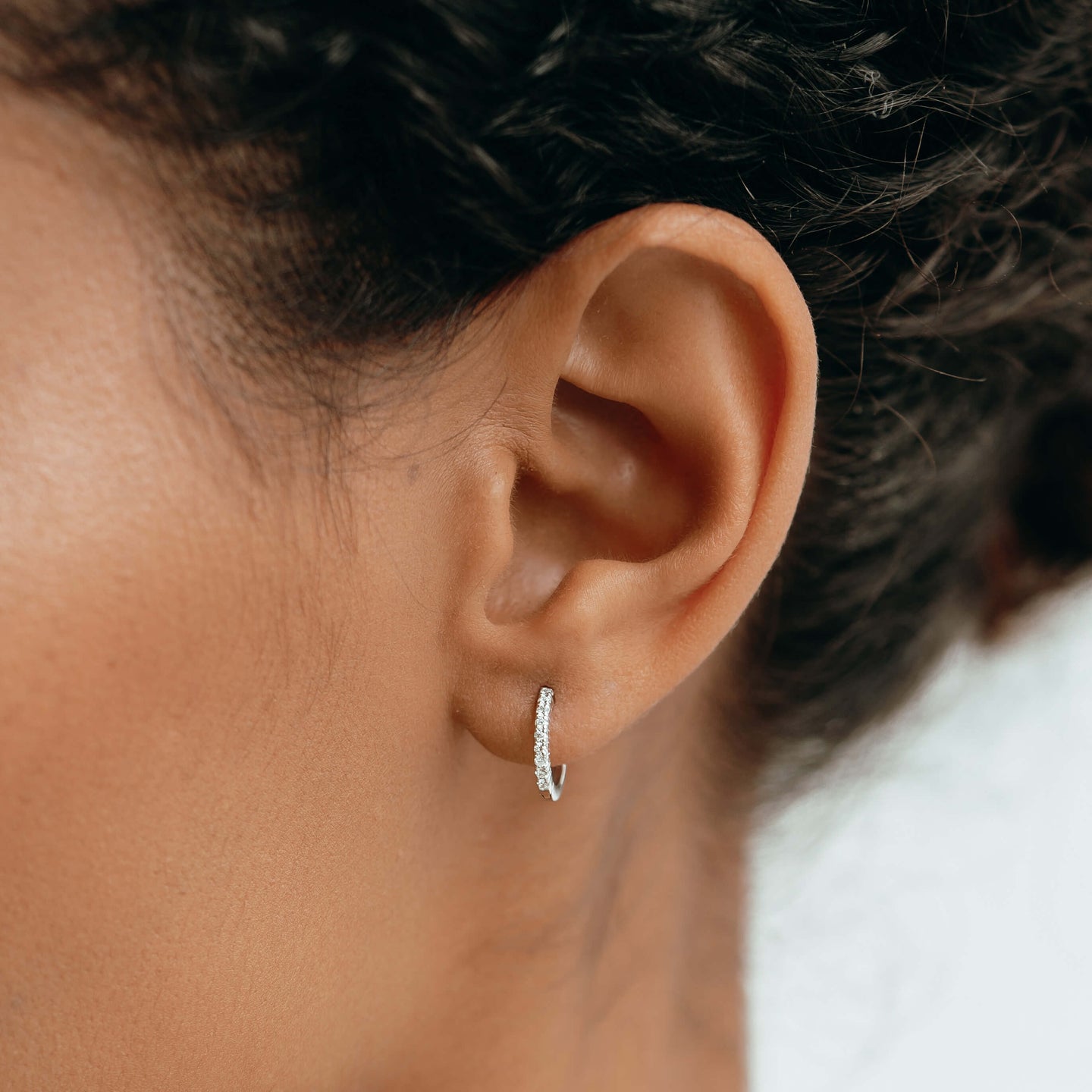 Diamond huggie earrings in 14k white gold on model