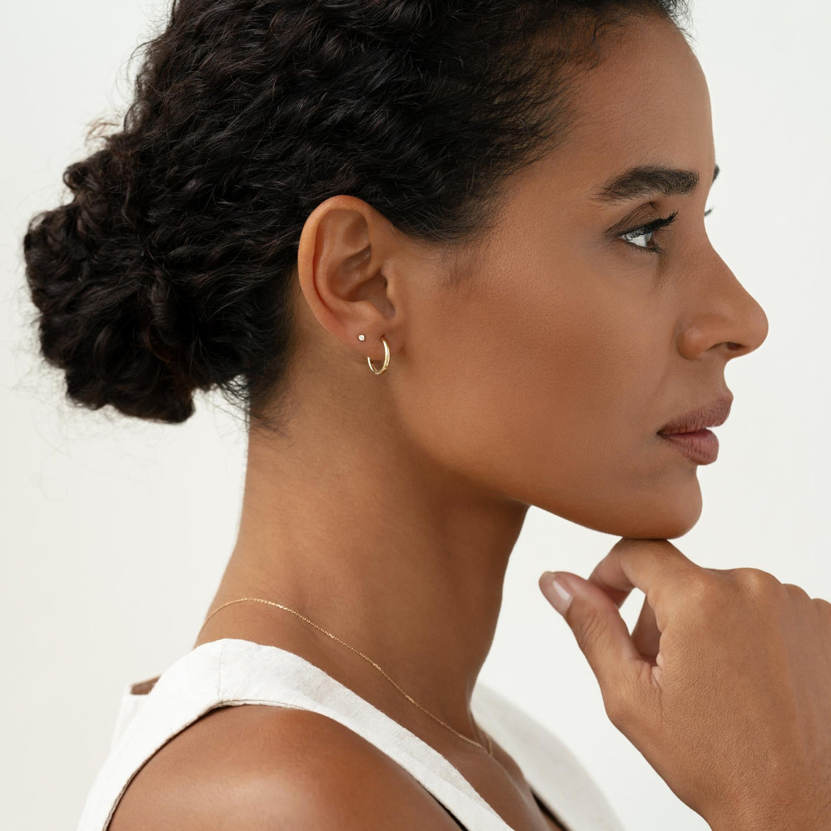 14k solid gold huggie earrings stacked with gold stud on model