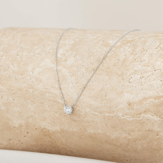 Elegant White Gold necklace featuring a sparkling diamond pendant, resting on a textured stone surface, perfect for any occasion.