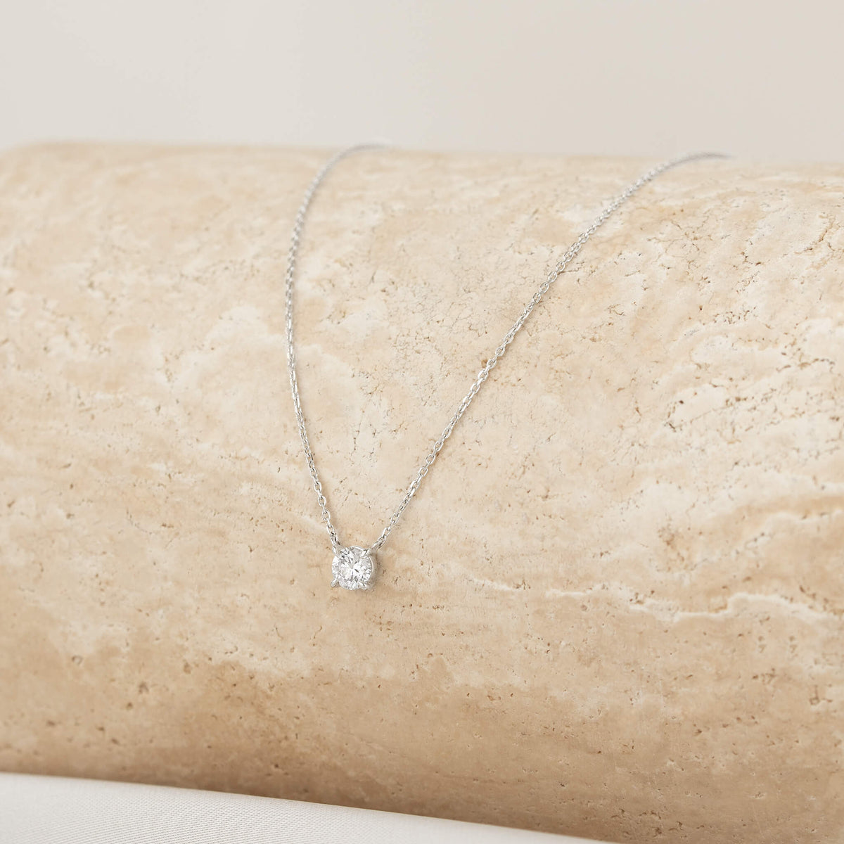 Elegant White Gold necklace featuring a sparkling diamond pendant, resting on a textured stone surface, perfect for any occasion.