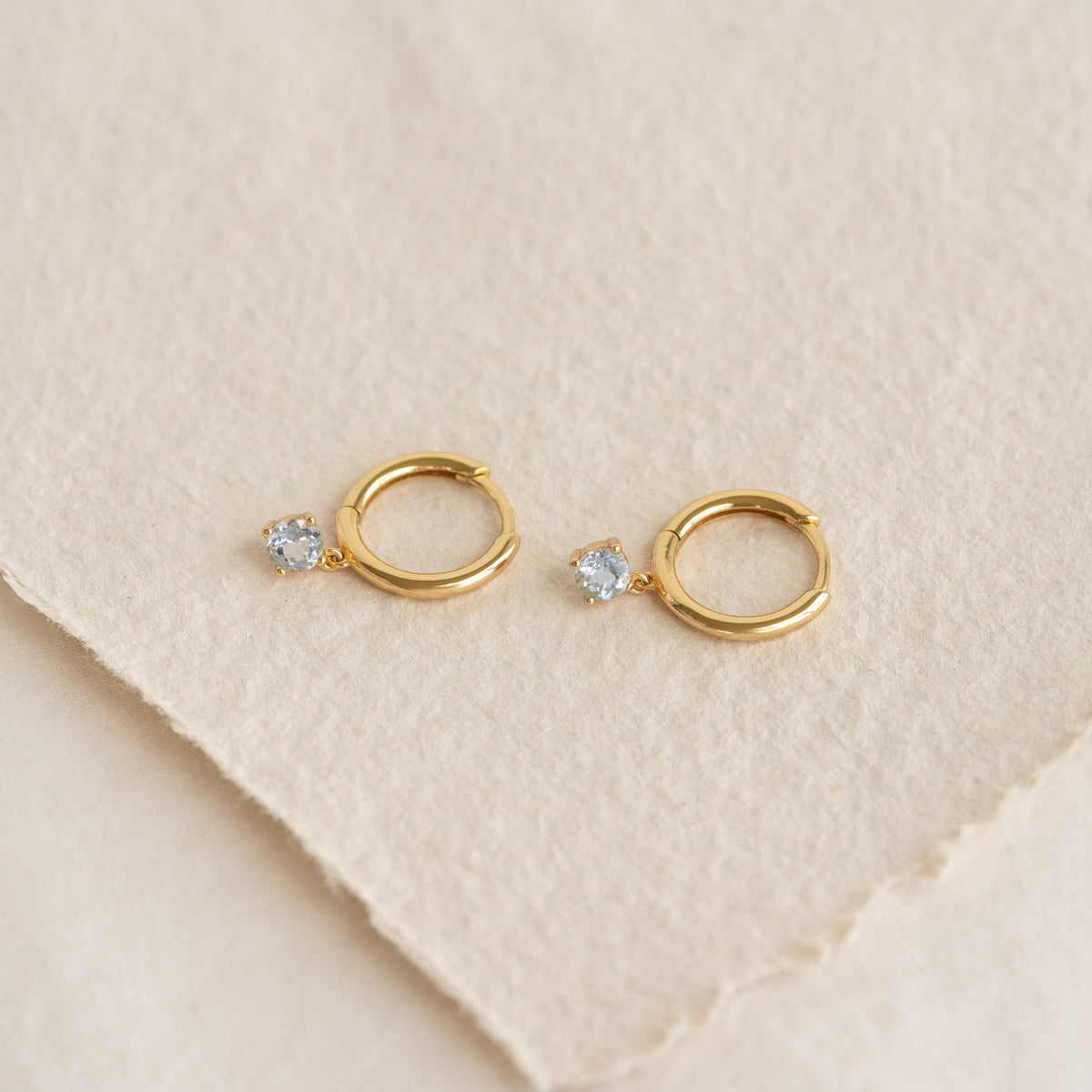 March Birthstone Drop Huggie Earrings - Aquamarine with pale blue gemstones set in gold vermeil on textured background