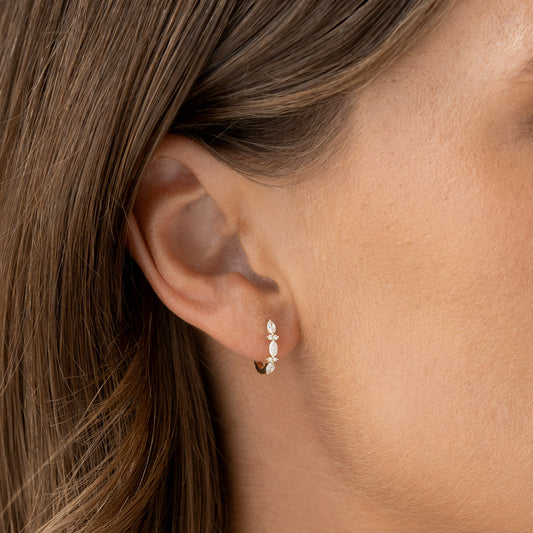 Close-up of a woman wearing Marquise and Round Diamond Huggie Earrings 14k Gold - Zoya on a neutral background
