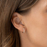 Close-up of a woman wearing Marquise and Round Diamond Huggie Earrings 14k Gold - Zoya on a neutral background