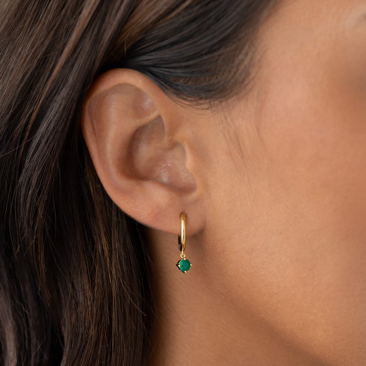 Close-up of an ear wearing May Birthstone Drop Huggie Earrings - Green Chalcedony with gold vermeil setting