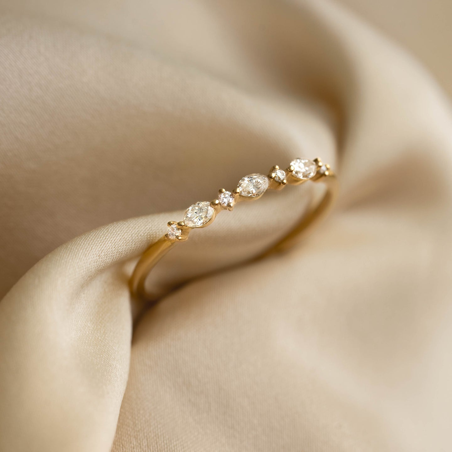 Marquise and Round Diamond Ring 14k Gold - Nova with three marquise cut and round diamonds on gold band on beige fabric background