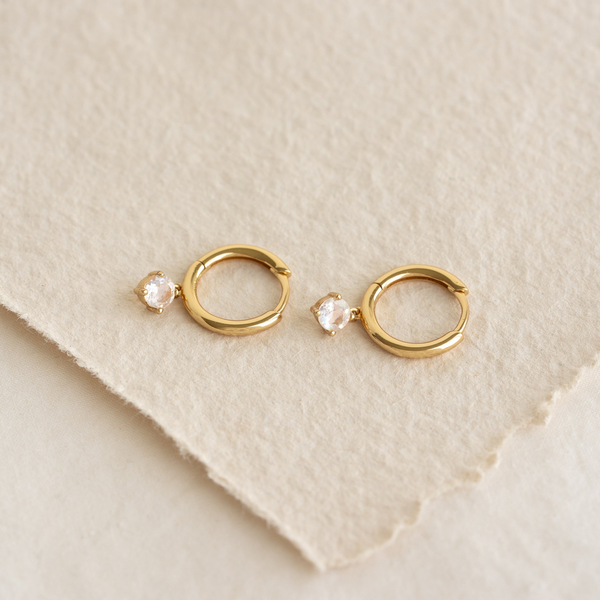June Birthstone Drop Huggie Earrings - Moonstone with gold vermeil setting on textured beige background