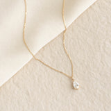 Pear Cut Diamond Pendant Necklace 14k Gold - Oline with a delicate chain on a soft beige textured background
