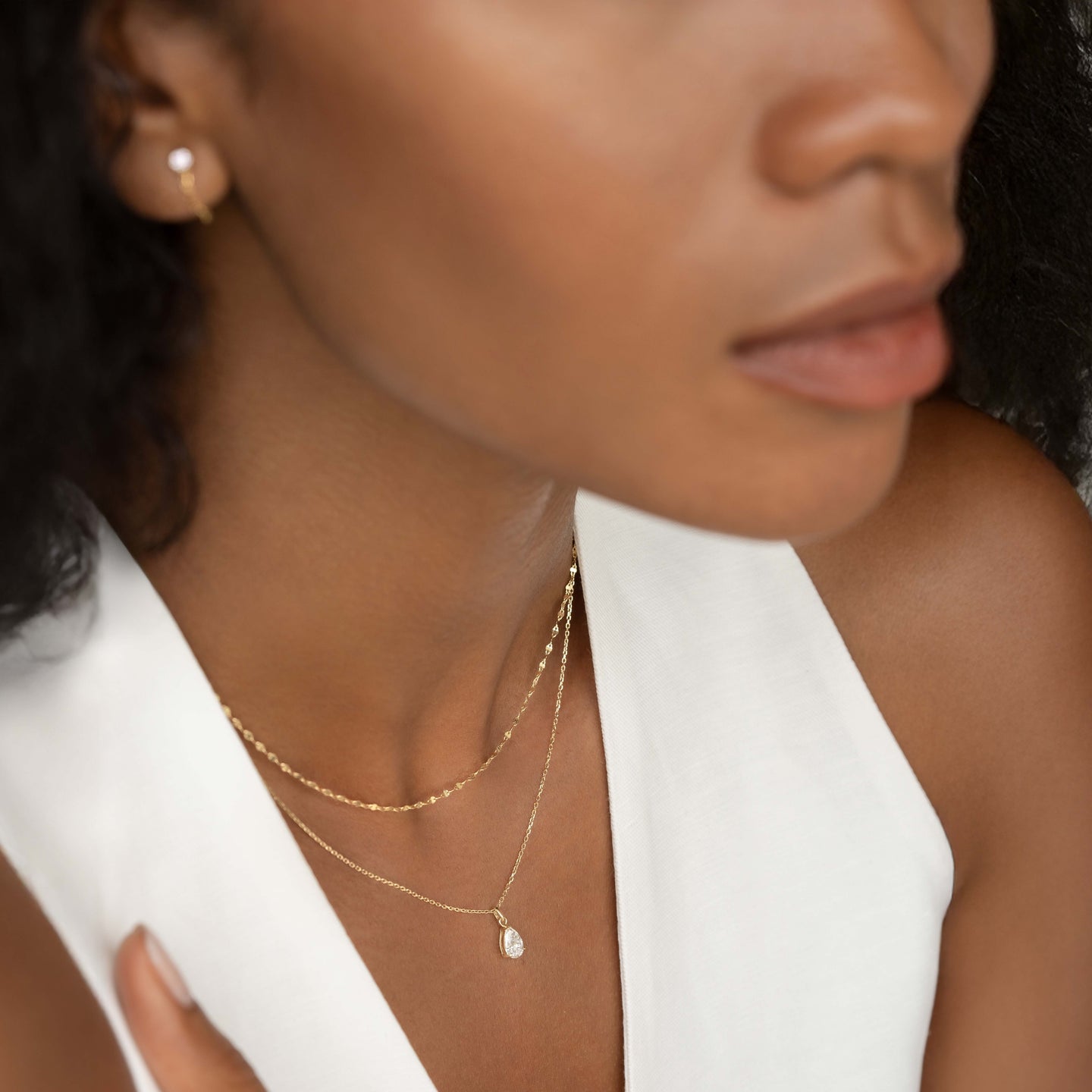 Close-up of woman wearing Pear Cut Diamond Pendant Necklace 14k Gold - Oline with delicate gold chains and white top