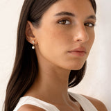 Close-up of a woman wearing Pearl Drop Earrings - Ariana with baroque pearls and cubic zirconia on a neutral background