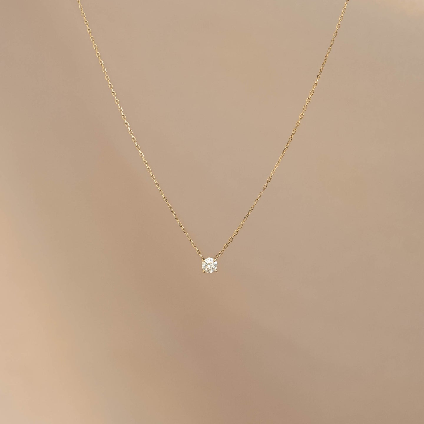 Diamond Pendant Necklace 14k Gold - Johanne with a delicate chain and a single floating diamond on beige background