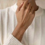Close-up of a hand wearing the Petal Chain Bracelet 14k Gold - Florence on a white textured sweater background
