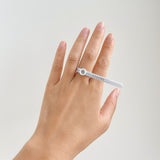 Hand with a white Ring Sizer wrapped around middle finger against a plain light background