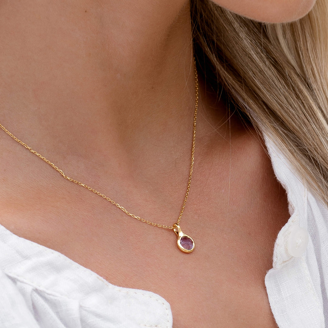 Close-up of a woman wearing an Amethyst Necklace - Sigrid on a delicate gold chain with a white top