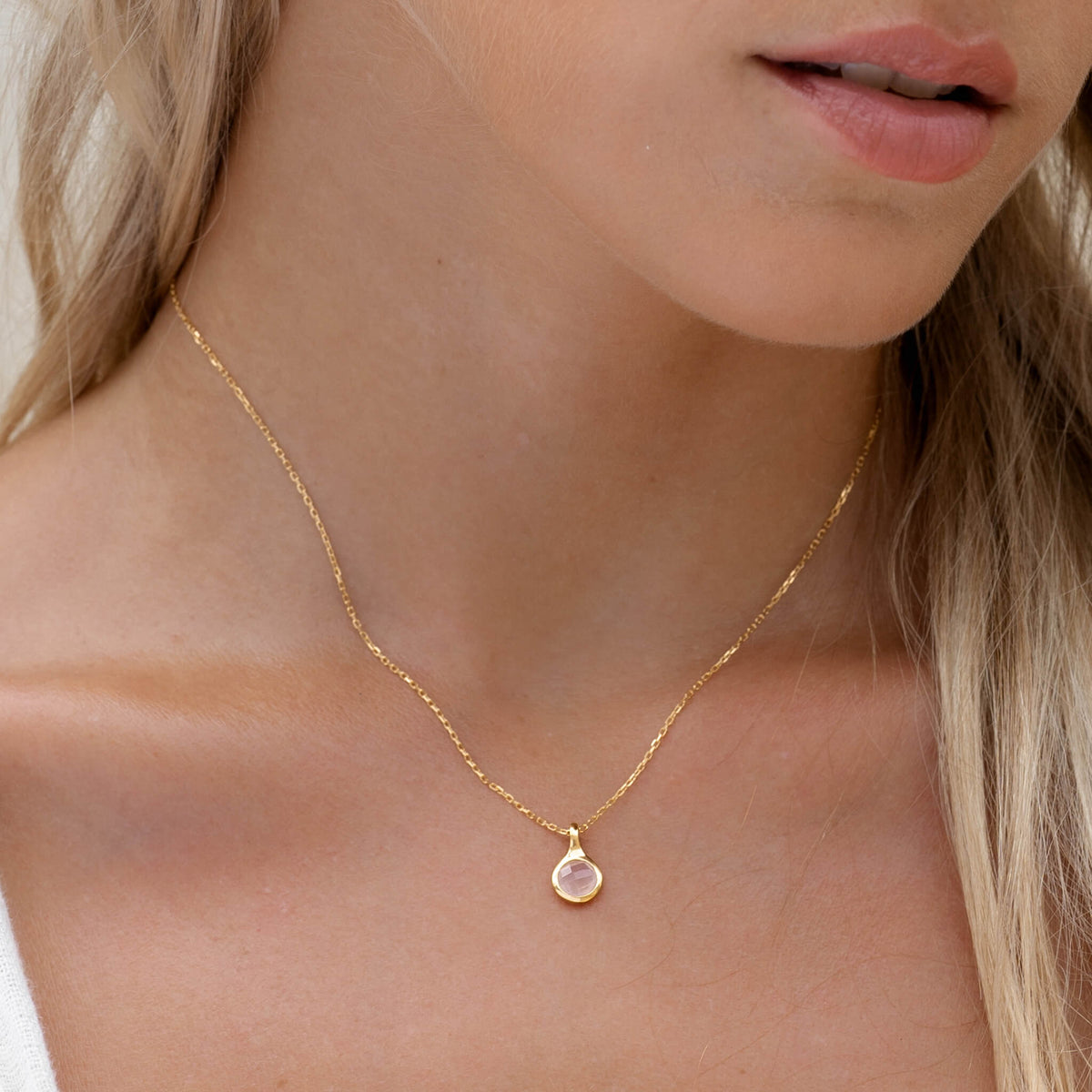 Close-up of woman wearing Rose Quartz Necklace - Sigrid with a hand-cut pink gemstone on a delicate gold chain