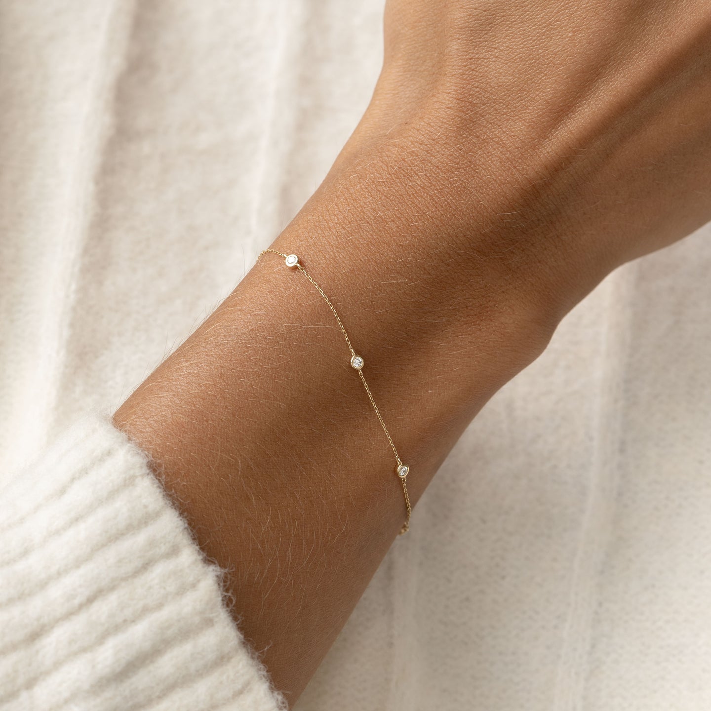 Bezel Set Diamond Bracelet 14k Gold - Vilda worn on wrist with cream knit sweater background