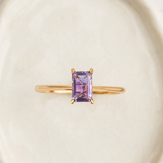 Baguette Ring Amethyst - Charlotte with a rectangular purple amethyst set on a slim gold band on a neutral background