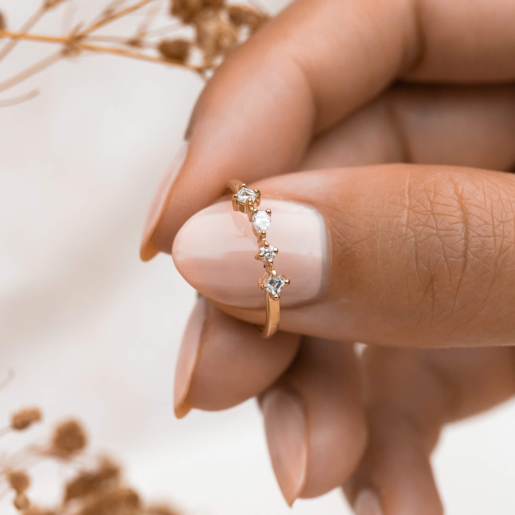 Four unique lab grown white diamonds on 14k yellow gold band on hand