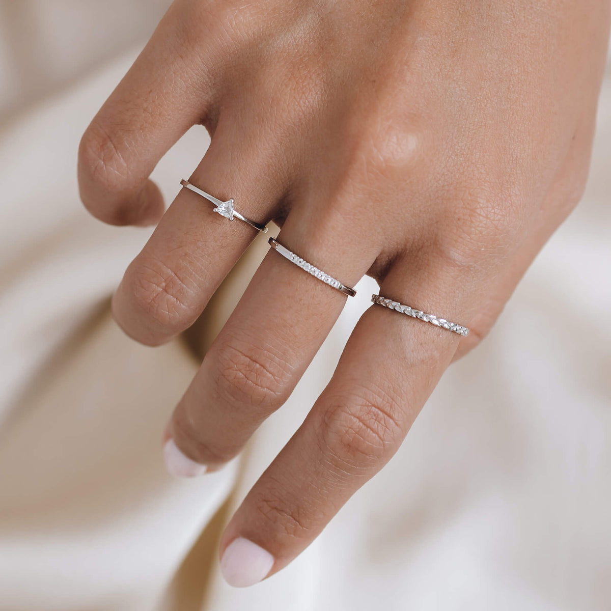 Stack of white topaz gemstone silver rings on model