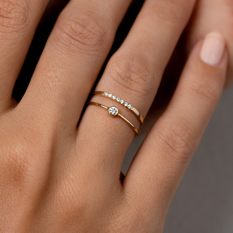Bezel-set diamond ring and diamond pave band on finger