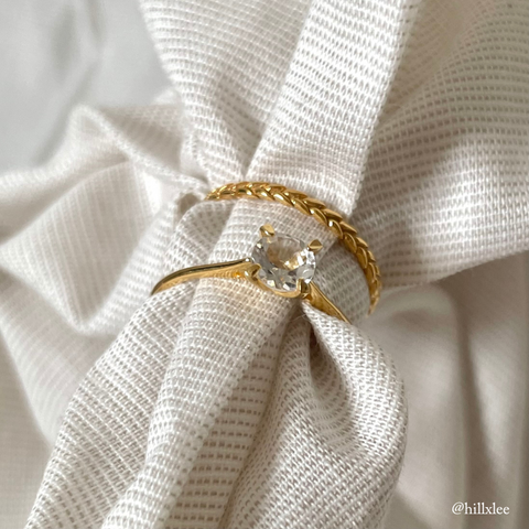 White topaz ring and braid ring standing on white fabric