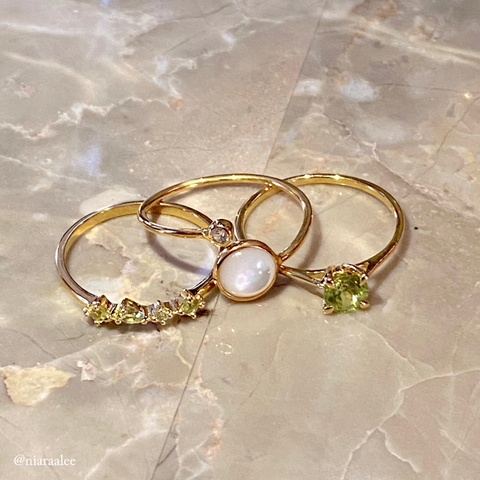 Peridot rings and mother of pearl ring in gold vermeil laying on textured background